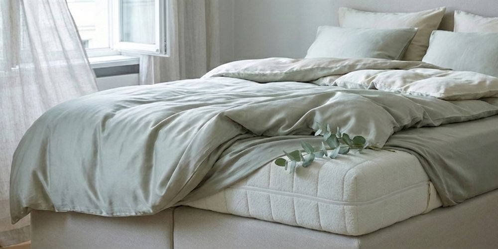 Natuurlijke slaapkamer met gestoffeerd bed en een natuurlijke eucalyptus tak op zacht Bedaffair Bio Tencel matras