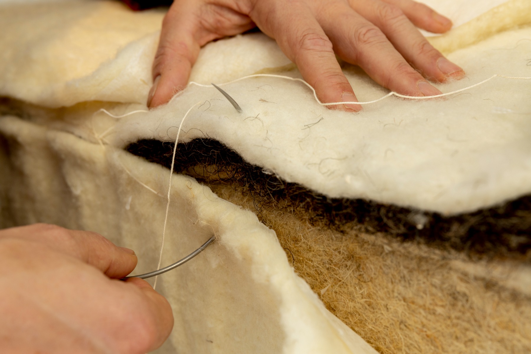 Merinowol omhuld de kern van een Bedaffair pocketvering matras en wordt met naald en draad vastgezet aan natuurlijke materialen
